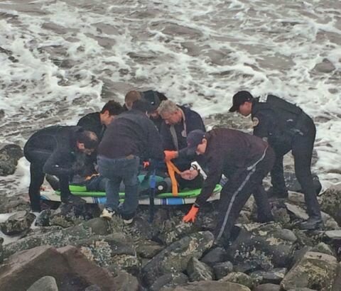 Emergency responders prepare the accident victim for transport across the groin to a waiting ambulance.
